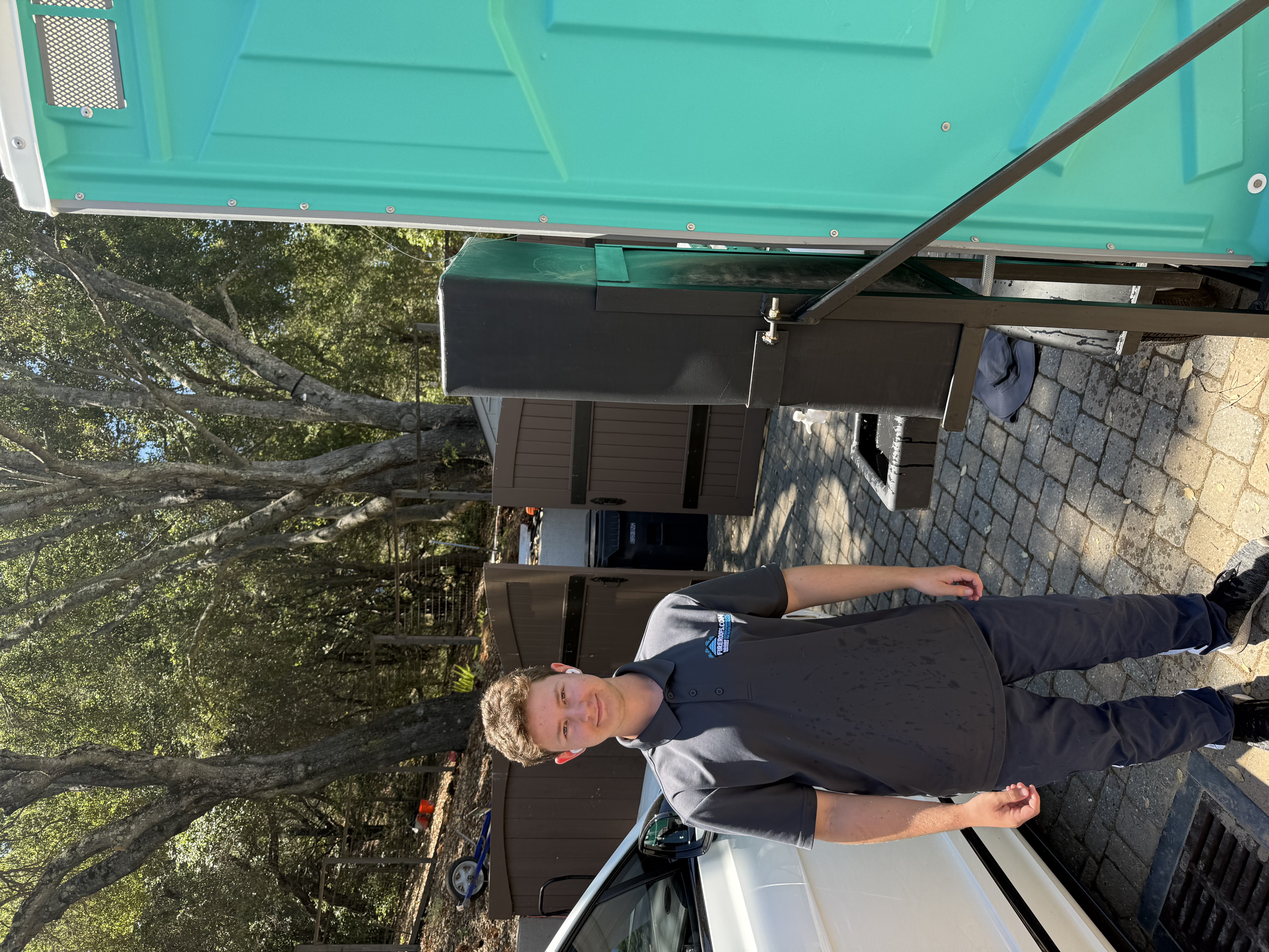 FireRoofs team member next to water storage tank at a residential installation