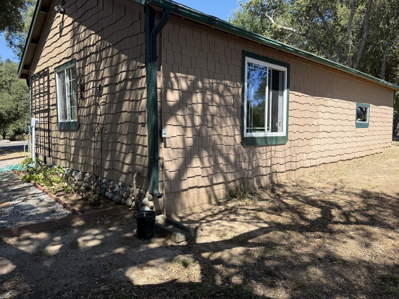 Hardie-shake fiber-cement siding covering both structures on a WUI home, with a gable vent and downspout visible