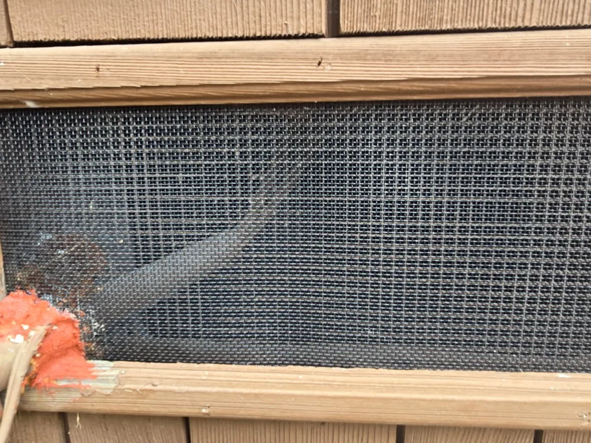 Completed ember-resistant crawlspace vent with stainless steel mesh and trim reinstalled on a Portola Valley home