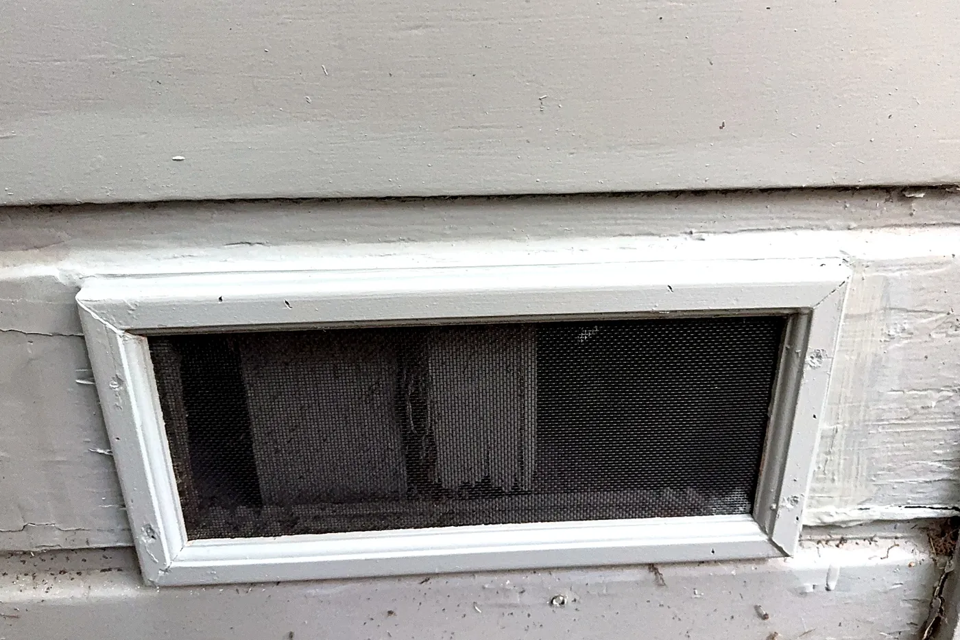 Foundation vent retrofitted with fine ember-resistant metal mesh and painted trim