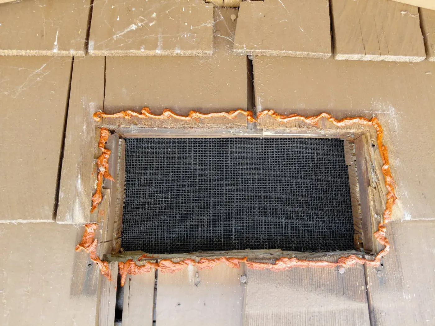 A foundation vent with the mesh in place and the full perimeter sealed so embers cannot slip behind it.