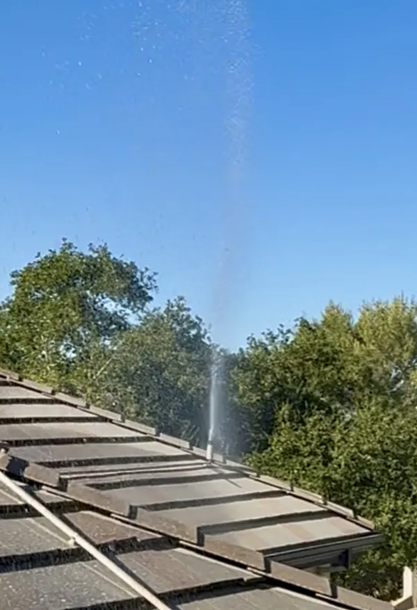 Roof sprinkler heads spraying water across a roofline during testing