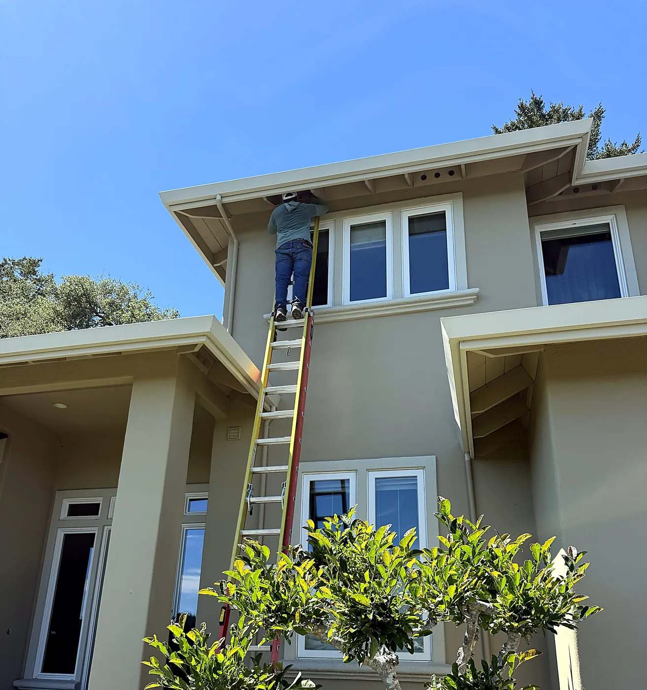 FireRoofs installer on a ladder screening eave vents on a two-story Scotts Valley home