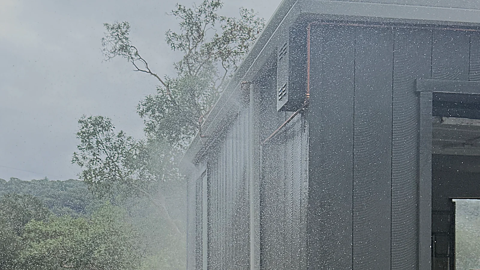 Eave sprinklers misting the eaves, walls and garage door of a Bay Area home to protect Zone Zero from embers and radiant heat