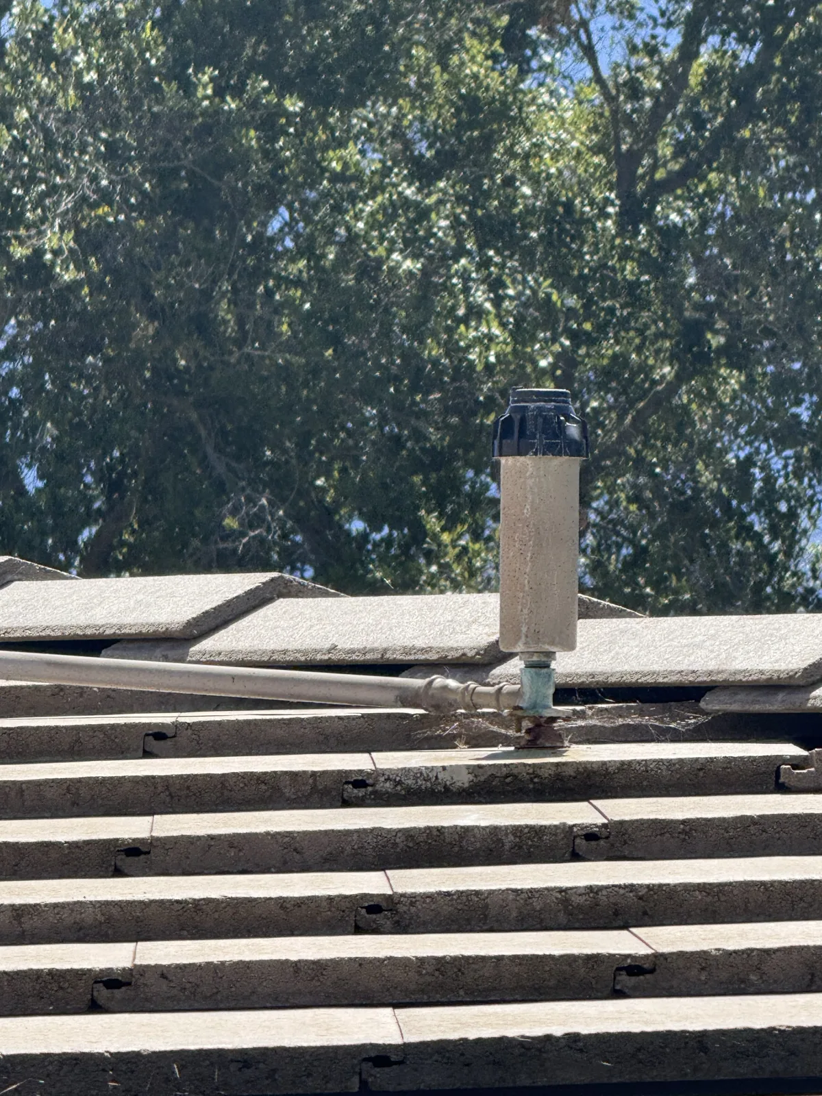 Low-profile roof sprinkler head on a riser installed on a concrete tile roof